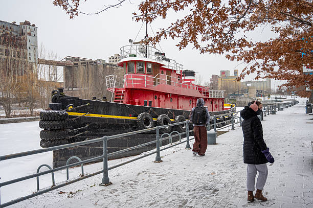 Teenager girl and boy besides abandoned tugboat in Lachine Canal in Montreal Old Port duting winter day