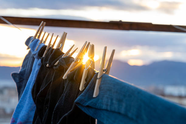 Clothes and socks hanging on a clothesline with wooden clothespins, drying outdoors against a dramatic backdrop of breaking dawn or setting sun and clouds