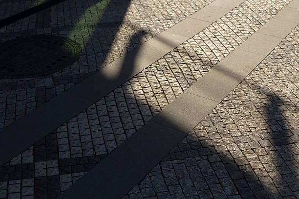 istock A persons shadow is cast upon a charming cobblestone sidewalk as well 2253707631