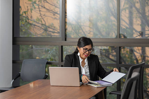 istock Businesswoman smiling while reviewing documents at office desk, managing work projects with expertise and precision 2253710182