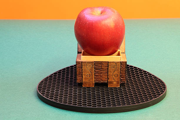 Still life with wooden carved chest and apple that did not fit in the chest, on mat with a honeycomb pattern. Photo with great depth of field.