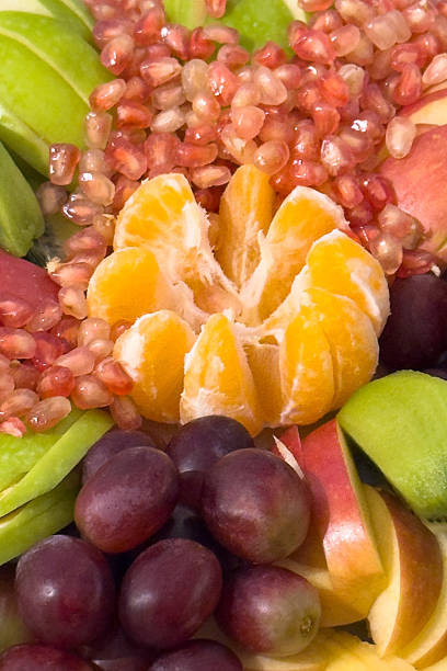 A fruit salad with a variety of fruits including apples, oranges, and grapes close-up