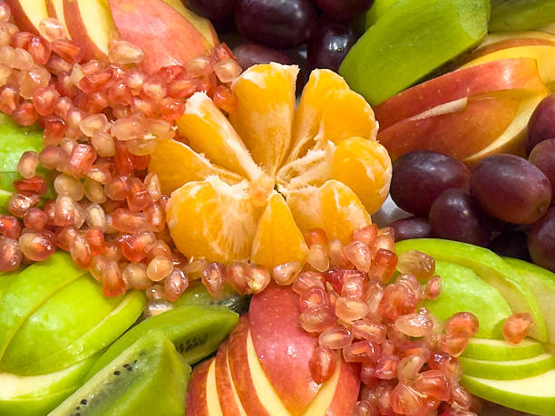 A fruit salad with a variety of fruits including apples, oranges, kiwis and grapes close-up
