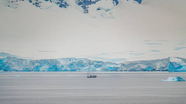 istock Small Sailboat in Neumayer Channel Antarctica Palmer Archipelago Dramatic Cliffs Snow Covered Mountains Calm Ocean. Natural Landscape Remote Adventure 2253731475