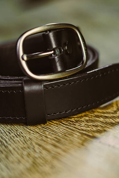 istock This stylish black leather belt, featuring a durable metal buckle, rests elegantly on a beautiful wooden surface, showcasing its sophistication and versatile appeal for any outfit or occasion 2253732467