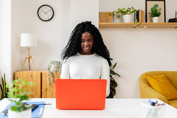istock Young business woman working on laptop computer sitting on table at home office 2253732531