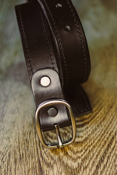 istock This highquality black leather belt features a sleek silver buckle. Showcased on rustic wood, it highlights its stylish design and craftsmanship, making it a perfect accessory for any outfit 2253732609