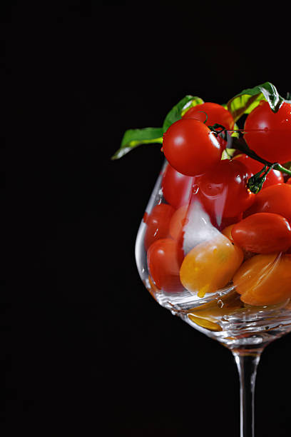 Closeup of cherry tomatoes in glass on black background