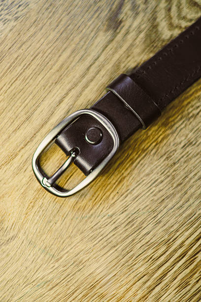 istock This brown leather belt features a sleek silver buckle and is showcased on a wooden surface, serving as a functional yet stylish accessory that enhances any outfit in your wardrobe 2253733009