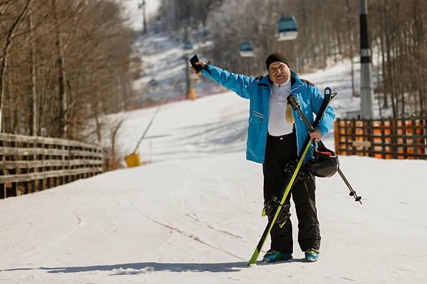 Happy female skier having fun while standing on a mountain with her arms raised during winter day. Copy space.