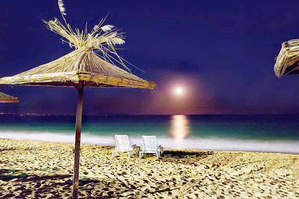 Stunning night on each - moon and sand on coastline  a. Thatched Awnings and 2  Beach chairs next to water
