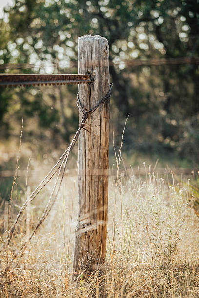 A rustic wooden fence post in an arid climate with barbed wire sets the land boundary.