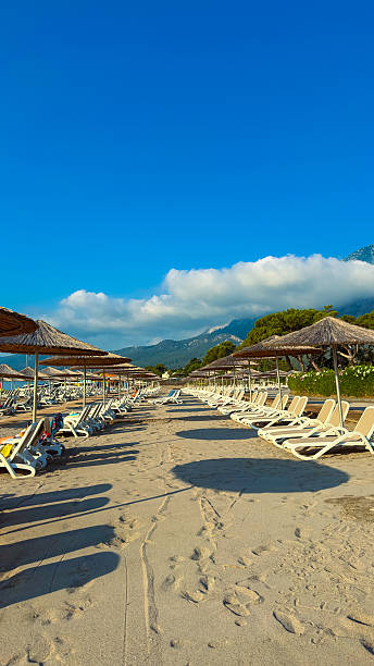 istock The serene beach has comfy lounge chairs under inviting shades, set against a bright blue sky and majestic mountains, making it ideal for relaxation and enjoyment for all visitors 2253737115