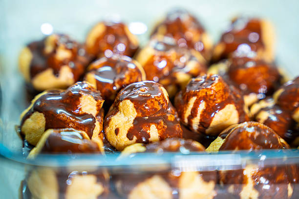 Chocolate Glaze Cascading Over Profiteroles in Clear Glass Container