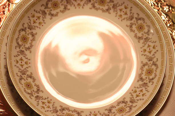 Elegant table setting featuring a decorated deep plate and a flat plate, both adorned with a delicate floral pattern, arranged on a luxurious golden charger. Ideal for concepts such as fine dining, festive table setting, luxury lifestyle, special occasions, holiday meals, elegant home decor, and sophisticated dining presentations.