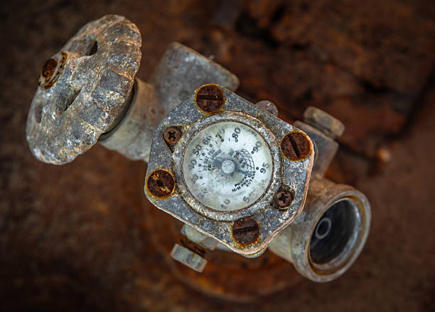 An old rusted gauge of a defunct propane tank valve shot from directly above with selective focus of dial.