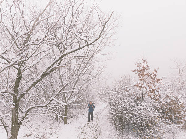 Man enjoy winter walk in nature in snowy fog mountain