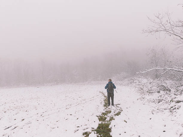 Man enjoy winter walk in nature in snowy fog mountain