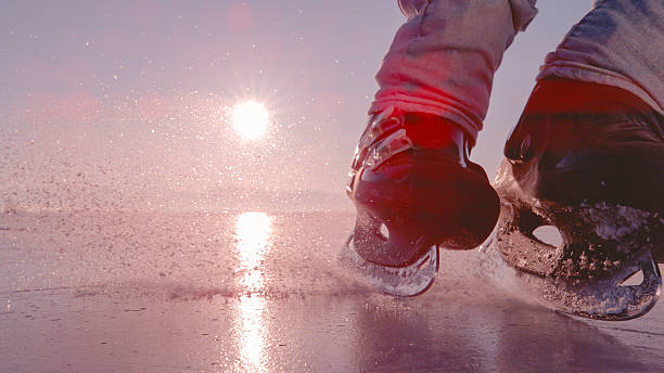 A tired child while skating. Reflection of the red setting sun on the ice of the frozen sun in the late evening