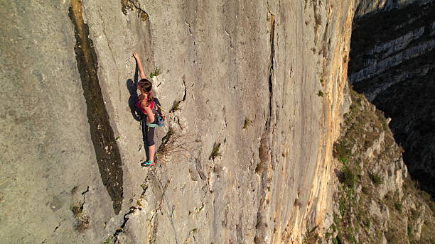 istock AERIAL, CLOSE UP: Young woman moving lead climbing a vertical limestone cliff 2253743691
