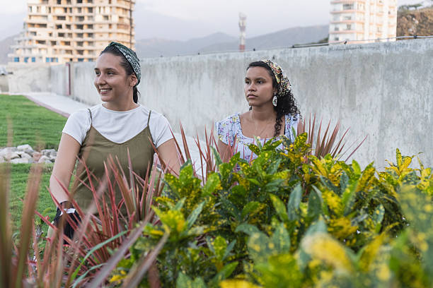 Two young women standing outdoors in a green rooftop garden with urban buildings in background