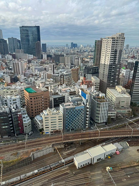istock VERTICAL: Tokyo's skyline stretches into the distance beyond rusty train tracks 2253743741