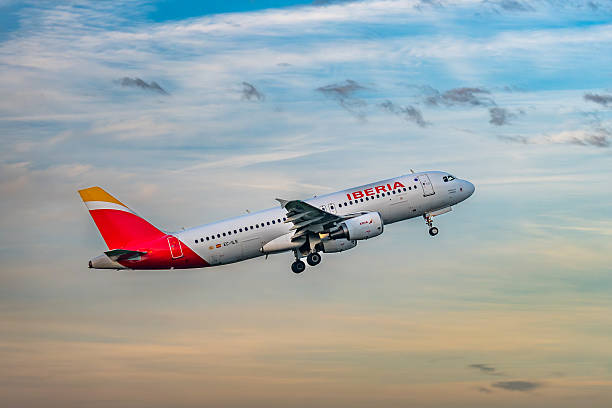 Brussels, Belgium - Dec 21, 2025: Iberia Airbus A320 narrow body passenger jet departing from Brussels Airport during sunset with landing gear extended.