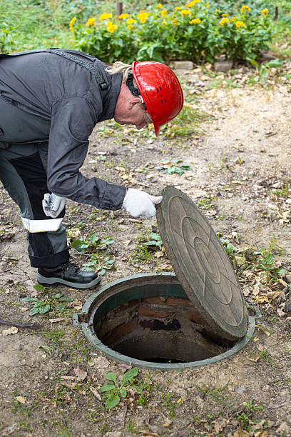 istock A worker opened the septic tank manhole cover and leaned over it. Maintenance 2253746907