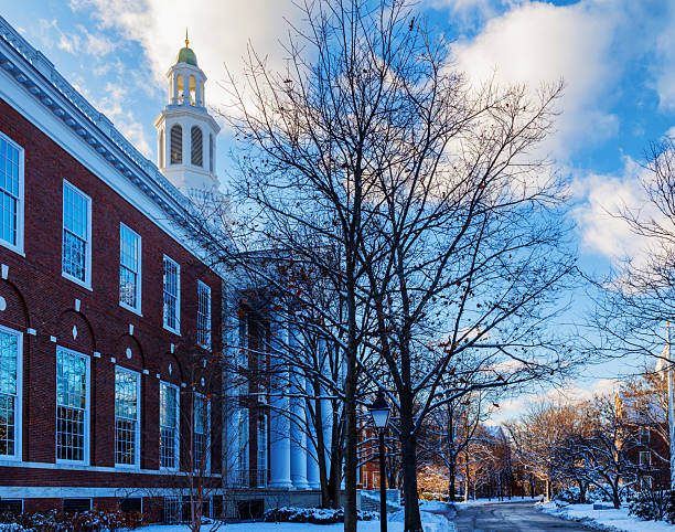 Boston, Massachusetts, USA - December 21, 2024: View along the Harvard Way road past the Baker Library during a winter sunset. The Harvard Business School's Baker Library was dedicated in 1927 and named for George F. Baker, the benefactor who funded Harvard Business School's original campus. It is the largest business library in the world. Harvard Business School (HBS) is the graduate business school of Harvard University, a private research university in Boston. It is consistently ranked among the top business schools in the world and offers a full-time MBA program, management-related doctoral programs, and executive education programs.