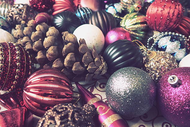 Brightly colored Christmas ornaments are artistically arranged with a pinecone, creating a vibrant festive atmosphere.
