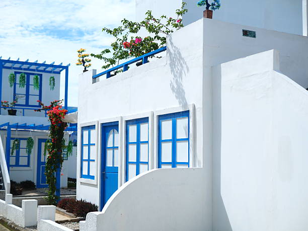 Charming white buildings with vibrant blue doors and windows under a clear blue sky, evoking a Mediterranean or Greek island aesthetic. Ideal for travel, vacation, and architectural themes.