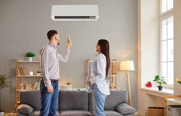 istock Young couple setting up a comfortable temperature on modern air conditioner by remote at home. 2253751033