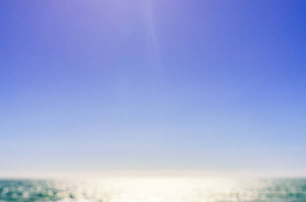 An intentionally defocused background of sea, brightly lit by a summer sun and a clear blue sky.