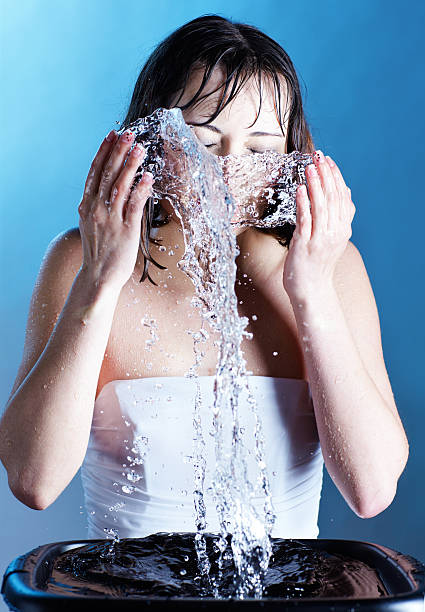 portrait of brunette female washing her face on blue