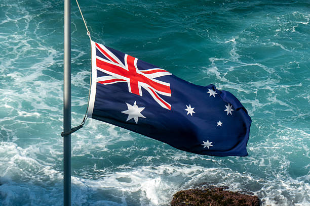 istock Half-Mast Australian Flag Breaking Waves 2253754457
