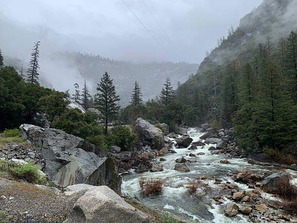 The Merced River tumbles down its rocky riverbed. A foggy haze settles in the valley. Yosemite, CA 2022