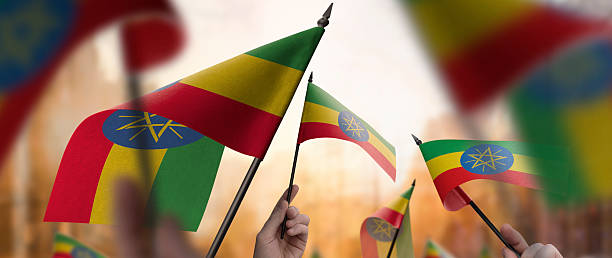 istock Ethiopia flags in their hands on a blurred urban background 2253757442