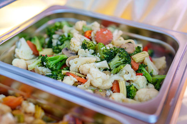 top view closeup of fresh mixed frozen vegetables with carrots peas broccoli and potatoes on round plate isolated on white background