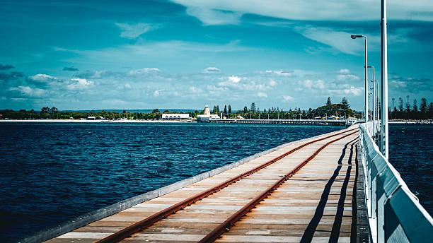 istock Wooden Pier With Train Tracks Extends Over Ocean Under Bright Sky 2253762572