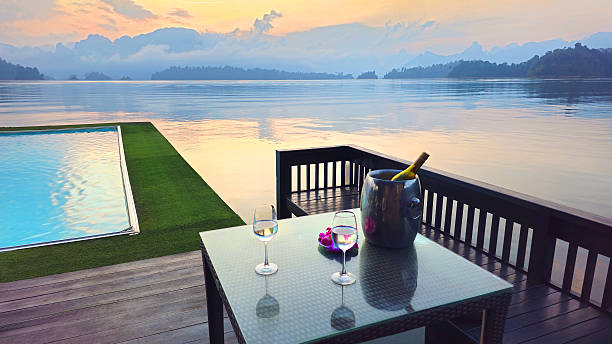 istock Table with two glasses and bottle overlooking  infinity pool and Cheow Lan Lake at sunset, Khao Sok National Park, Thailand, Southeast Asia. 2253763977