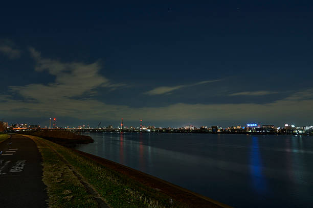 Amidst the deep silence of night, lights from the opposite buildings stretch across the water, appearing as if stardust is dissolving into the depths.