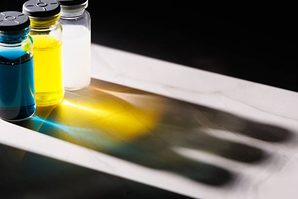 Diverse vaccine bottles with colored fluids and light reflections on a marble tabletop against a black background showing modern medical chemistry.