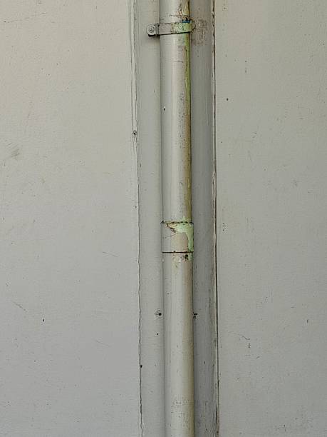 istock Aged White Wall with Grungy Vertical Pipe and Metal Clamp 2253771898