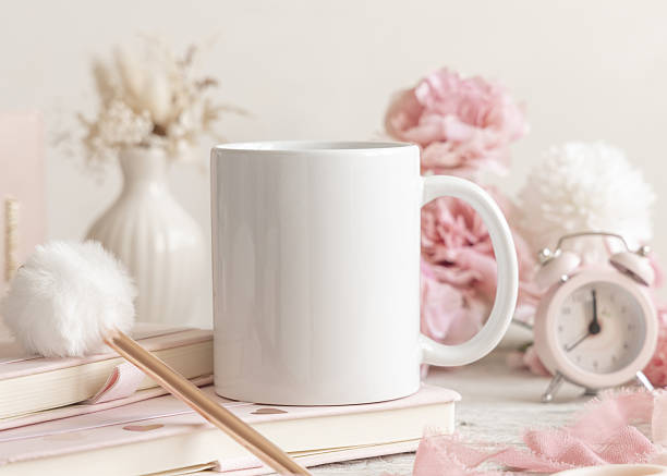 White ceramic coffee mug 11oz near pink decor and flowers, mockup, closeup, copy space. Pastel spring romantic scene for Valentines or Mothers day. Template for print on demand design