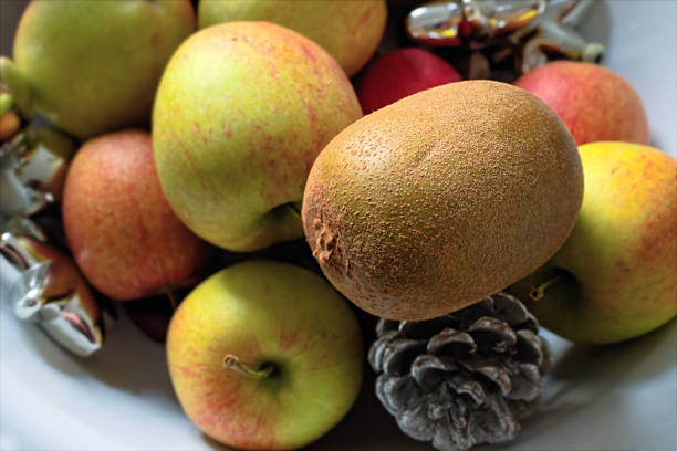 Close-up still life featuring apples and a kiwi arranged in a bowl with natural textures and warm tones. The organic composition highlights seasonal produce and rustic detail, with soft focus areas that provide subtle copy space for food, lifestyle, or sustainability concepts.
