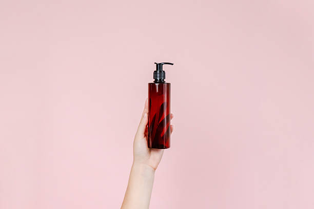 istock Blank bottle mockup in hand isolated on solid red background. Package for cosmetics product, your brand, spa, beauty and luxury. Space for text 2253778600