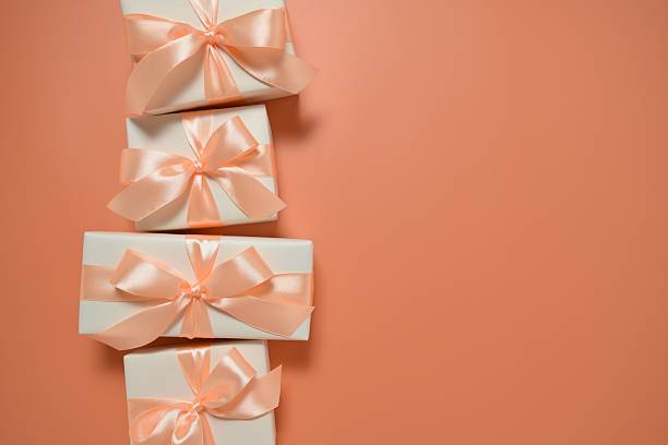 Four gift boxes with satin ribbons on an orange background