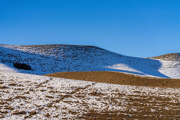 A stunning view from Bjelašnica mountain, showcasing Treskavica mountain in the background with its rocky, snow-covered peaks. The foreground features rolling grass-covered hills, creating a captivating contrast between the rugged and serene landscapes. An ideal image for promoting Bosnia and Herzegovina as a destination for travel, hiking, and nature exploration.