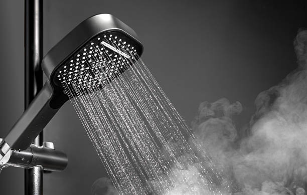 istock Shower head with running water in black bathroom 2253781904