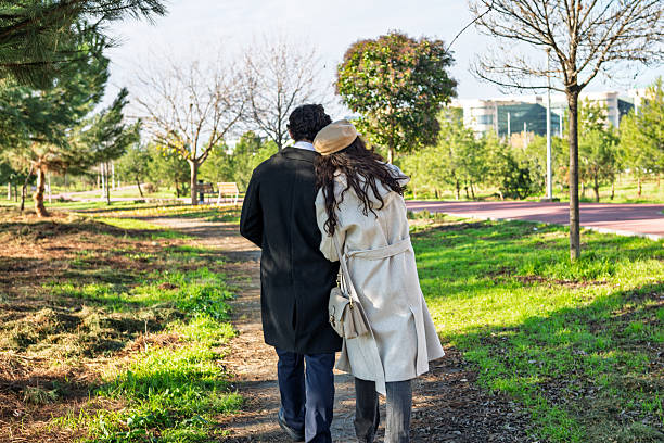 Young couple walking together, woman's head resting on man's shoulder